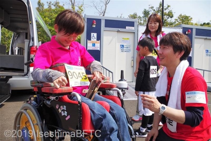 一緒に走る車いす使用者とコミュニケーションをとるボランティア